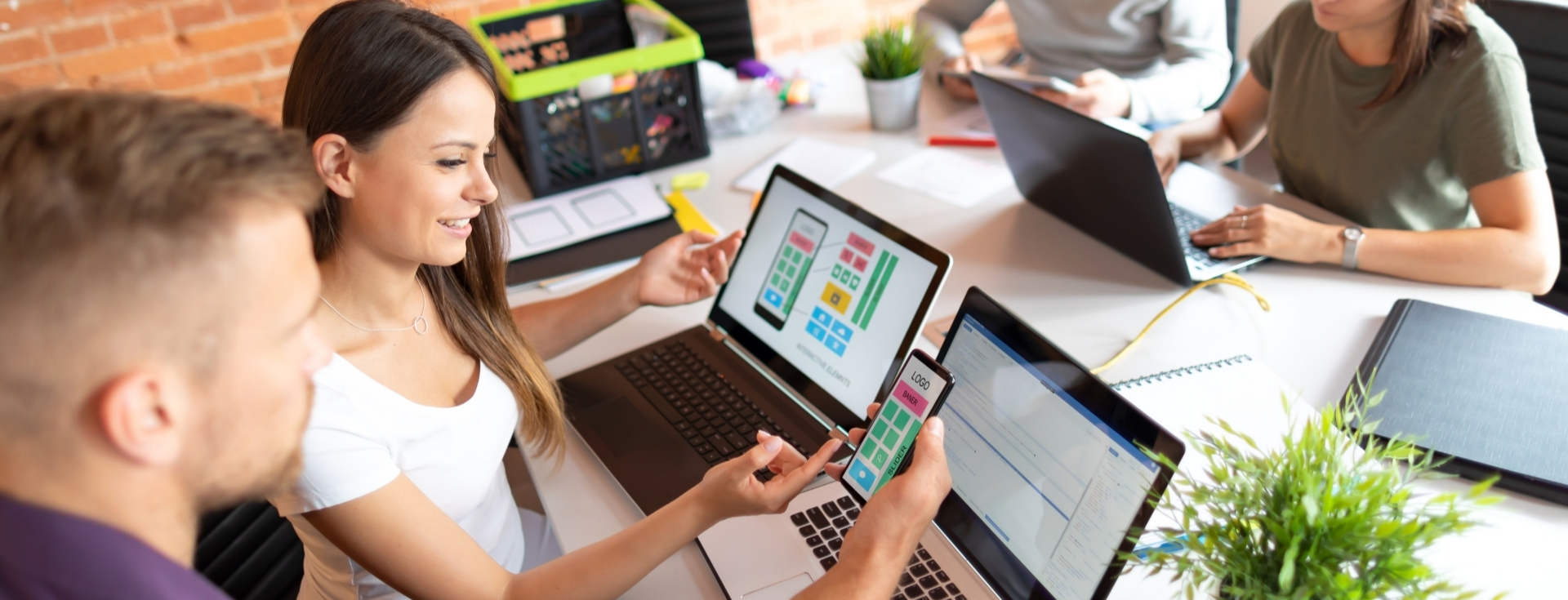 A group of people is working on laptops, engaged in various tasks. They are indoors, surrounded by a casual learning atmosphere. Each individual is focused on their personal computers, highlighting collaboration and productivity among the group.